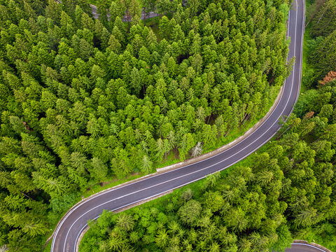 Winding road through the forest, from high mountain pass, in summer time. Aerial view by drone. Romania