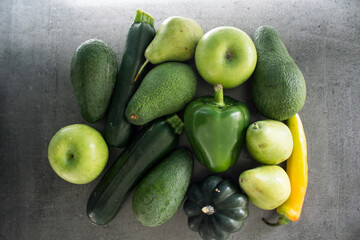 Green fruits and vegetables on a table. Top view photo of organic avocado, pepper, apple, pear, zucchini . Healthy eating concept. 