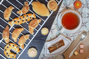 Fresh pastries on a white grill and tea, top view on a wooden background