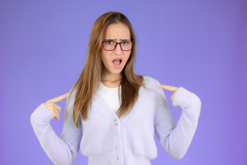 Portrait of young girl in casual sweater pointing thumbs herself isolated over purple background