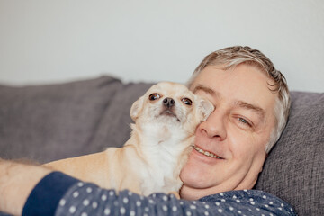 Caucasian man 47 years old hugging with love at his mini beige chihuahua dog