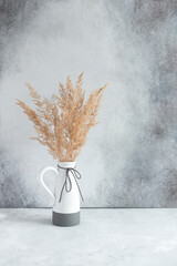 Pampas grass in ceramic vase against wall. Still life bouquet of dried flowers on stone background...