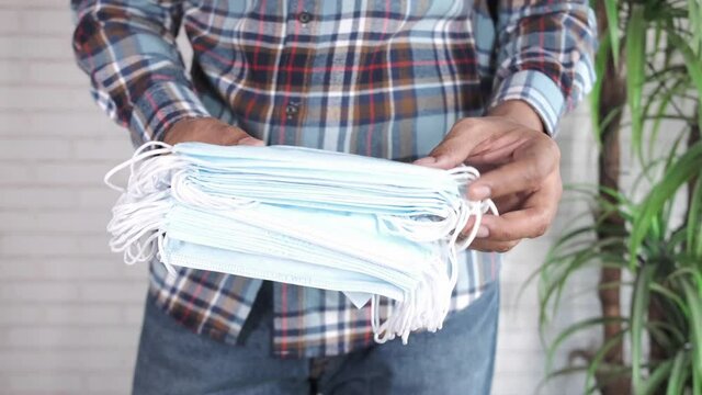  man hand holding stack of surgical face mask,