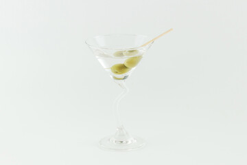 Martini cocktail with green olives on white background