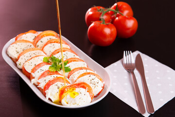 Caprese salad with some olive oil splashing on it