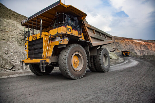 Rudny, Kazakhstan - May 14, 2012: Open-pit Mining Iron Ore In Quarry. Caterpillar Quarry Trucks Transporting Ore To Concentrating Plant. Rocks Of Minerals On Background.