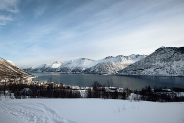 Scenery of snow mountain range and norwegian village on coastline in winter at Senja Island