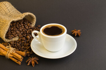 Obraz na płótnie Canvas Black coffee in the white cup,cinnamon and coffee beans on the dark background