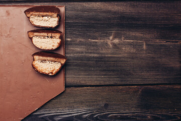 Obraz na płótnie Canvas halved brownie and chocolate bar on wooden table