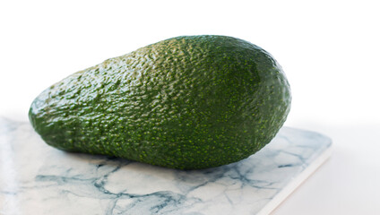 one whole green avocado close up on a light background