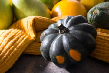 Small decorative squash and two oranges on a table. Yellow background. Fresh seasonal fruits and...