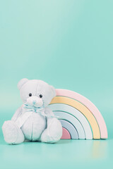 Toy teddy bear and pastel color wooden rainbow on light blue background. Baby kid toys background