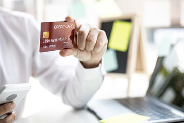 Men hold credit cards and fill in their card information to pay for purchases on the website, credit cards can be used to pay for goods and services with general merchants or online shopping.