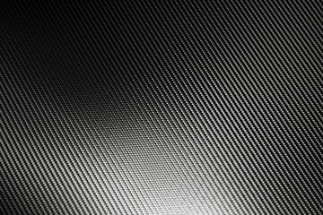 Bended surface of grey woven carbon fibre composite sheet.