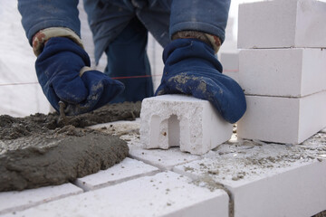 Mason lays bricks set in cement, making the masonry walls,the construction of the house.The worker aligns the blocks.