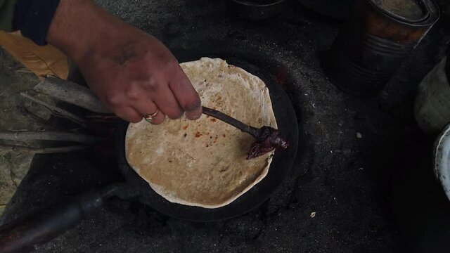 Man cooking Indian flat bread, roti paratha and roasting it on live flame. 