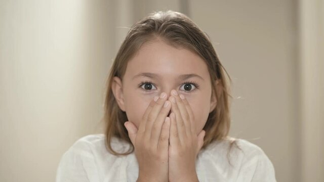 Surprised and shocked child girl face. Portrait expression little kid with brown-eyed looking at camera closeup. Wow emotion.