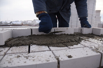 The builder puts the bricks in the cement mortar, will make the masonry wall of the new building.