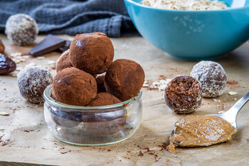 Healthy energy protein balls with dates, oats, peanut butter and dark chocolate. Homemade gluten free truffle bites covered with cocoa powder or almonds. Vegan raw appetizer or food snack. Side view.