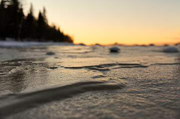 Fototapeta na wymiar Close-up frozen lake ice surface at sundown