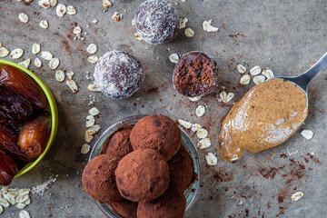 Healthy energy protein balls with dates, oats, peanut butter and dark chocolate. Homemade gluten free truffle bites covered with cocoa powder or almonds. Vegan raw appetizer or small snack. Top view.