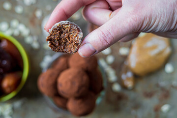 Selective focus on half eaten healthy energy protein ball with dates, oats, peanut butter and dark chocolate. Homemade gluten free truffle bites covered with cocoa powder or almonds. Vegan appetizer