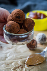 Hand holding healthy energy protein balls with dates, oats, peanut butter and dark chocolate. Homemade gluten free truffle bites with no bake. Vegan raw appetizer or small tasty snack. Side view