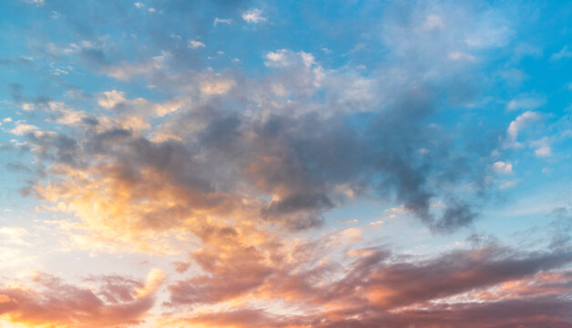 Natural sky background. Bright sunset with orange and blue clouds.