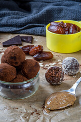 Healthy energy protein balls with dates, oats, peanut butter and dark chocolate. Homemade gluten free truffle bites covered with cocoa powder or almonds. Vegan raw appetizer or small snack. Side view.