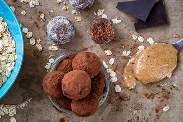Healthy energy protein balls with dates, oats, peanut butter and dark chocolate. Homemade gluten free truffle bites covered with cocoa powder or almonds. Vegan raw appetizer or small snack. Top view.