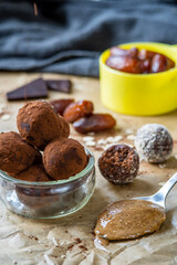 Healthy energy protein balls with dates, oats, peanut butter and dark chocolate. Homemade gluten free truffle bites covered with cocoa powder or almonds. Vegan raw appetizer or small snack. Side view.