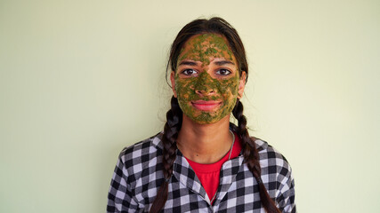 Portrait of a young girl with green Ayurvedic face packs isolated on white background. Women using...