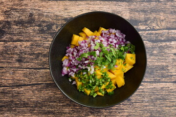 Preparing fresh homemade mango salsa in a bowl. Flat lay