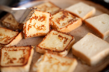 Yummy square-shaped  croutons fried in a pan. Homemade food, breakfast. White bread in egg fried in a pan with butter. Home kitchen. Croutons flip with a fork.