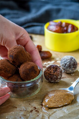 Hand holding healthy energy protein balls with dates, oats, peanut butter and dark chocolate. Homemade gluten free truffle bites with no bake. Vegan raw appetizer or small tasty snack. Side view