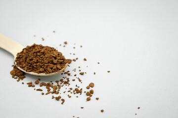 A wooden spoon with instant coffee on the table. Light background. Coffee scattered around. No waste concept. Space for the text on the right.