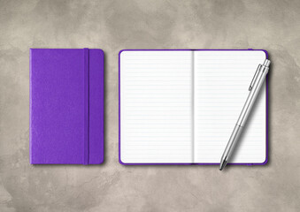 Purple closed and open lined notebooks with a pen on concrete background