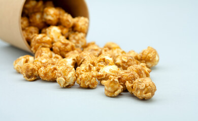 Popcorn spilled out of a paper cup. Close-up. Caramelized popcorn. Macro photography.