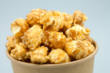 Caramelized popcorn in a paper cup. Close-up. Eco concept, craft paper cup. Macro photography.