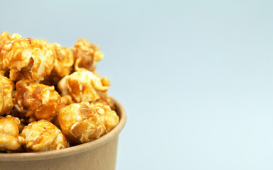Caramelized popcorn in a paper cup. Close-up, macro photography. Cropped in half. Free space for text on the right.