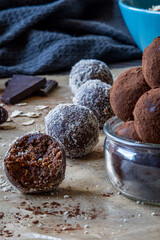Close up and selective focus on healthy energy protein balls with dates, oats, peanut butter and dark chocolate. Homemade gluten free truffle bites covered with cocoa powder. Vegan raw appetizer.