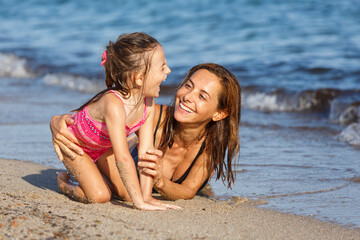 Fototapeta premium Madre gioca simpaticamente con la figlia al mare in spiaggia