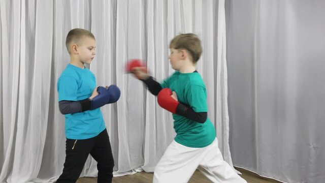 Two athletes in multi-colored T-shirts and pads on their arms train blocks and punches to meet each other