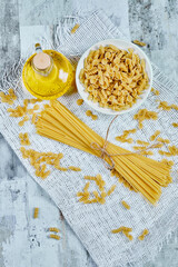A bowl of uncooked pasta and spaghetti on a marble background 