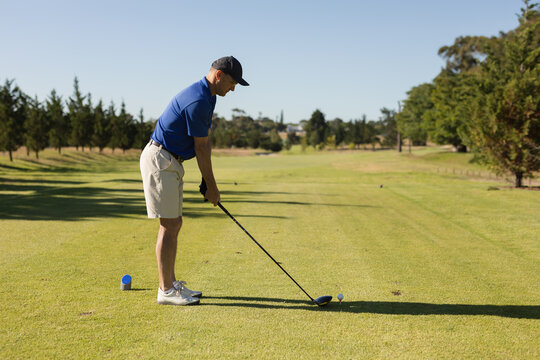 Caucasian senior man holding golf club preparing for shot on the green