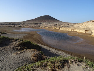 Fototapeta na wymiar Natural pond in the Beach of El Médano and the Red Mountain in the rear. South of Tenerife. Canary Islands. Spain. 