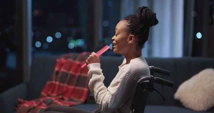 Happy african american young woman singing song in wheelchair swinging around house enjoying evening concert home activity entertainment.