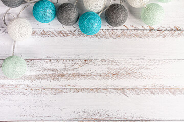 a garland of white, gray and blue balls on white wooden background
