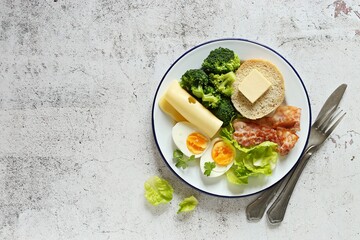 Low carb breakfast with egg, fried bacon, broccoli and gluten free keto bread. Flat layot, copy space
