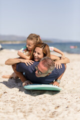 Allegra famiglia composta da padre, madre e figlia si diverte giocando con con una tavola da surf...